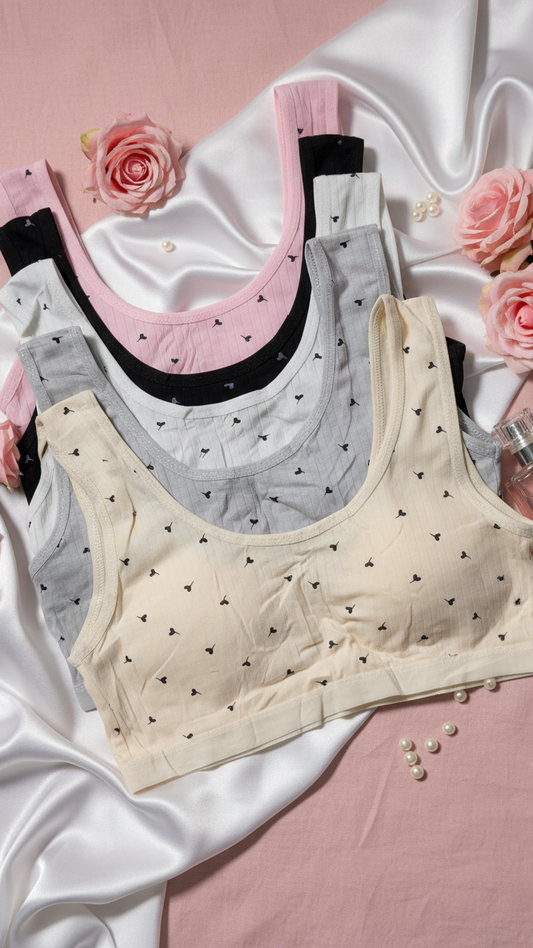 Two bras on a pink fabric background with flowers and a perfume bottle.