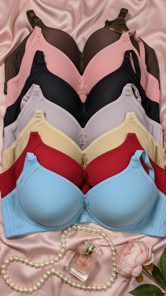 Set of colorful bras on a pink satin background with flowers and a necklace.